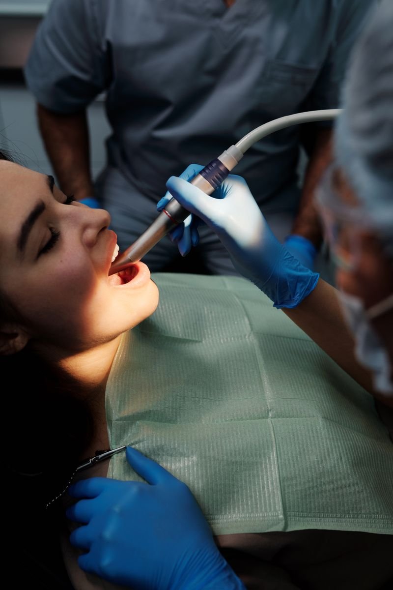 Woman receiving dental treatment in clinic, dentist using specialized tools.