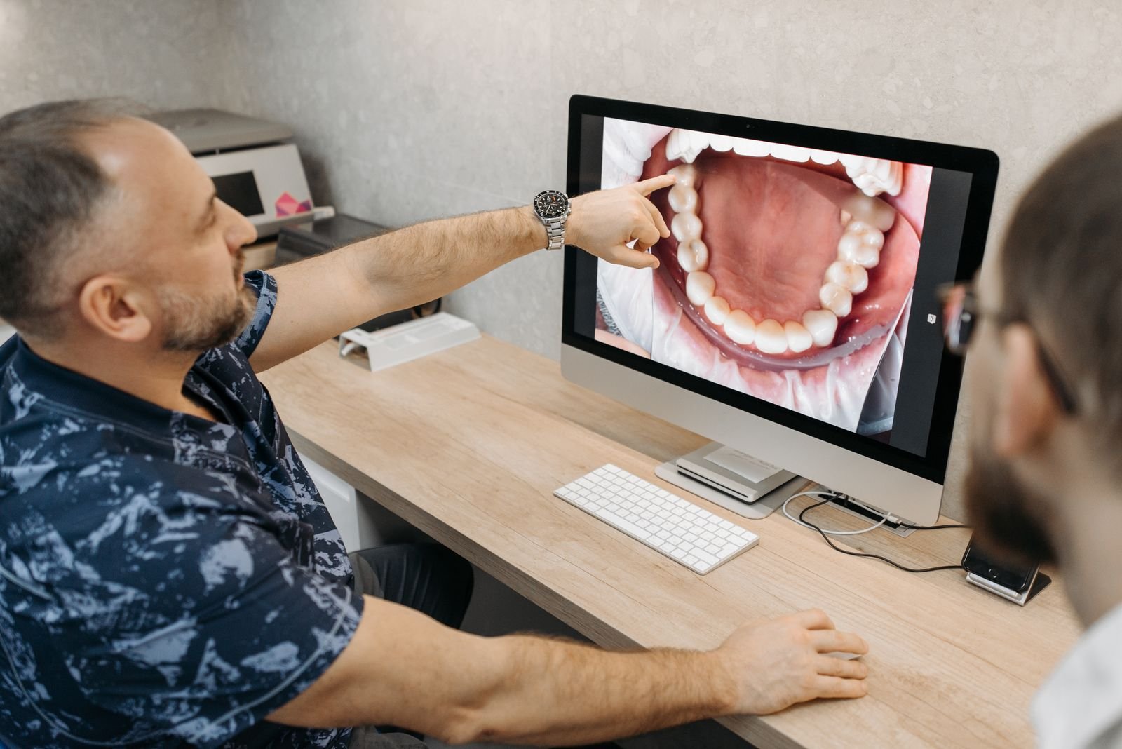 Dentist explains dental condition using intraoral images on a computer screen.