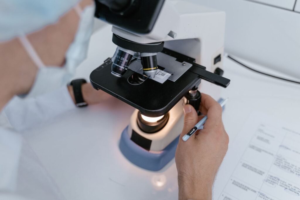 AI Caries Detection: High Scores, Shaky Evidence? Close-up of a scientist examining samples under a microscope in a laboratory setting.