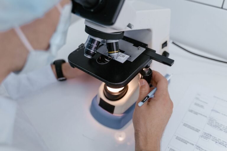 AI Caries Detection: High Scores, Shaky Evidence? Close-up of a scientist examining samples under a microscope in a laboratory setting.
